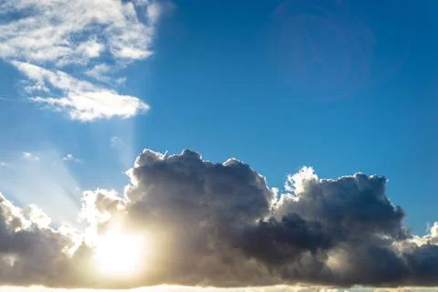 Clouds and sun in a blue sky at sunset Stock Photos