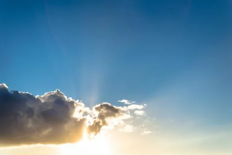 Clouds and sun in a blue sky at sunset Stock Photos
