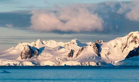 Clouds and sunset light over snow-capped mountains and icebergs, Antarctica Stock Photos