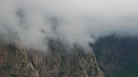 Clouds are flowing over mountain peaks in a valley 動画素材 289665830