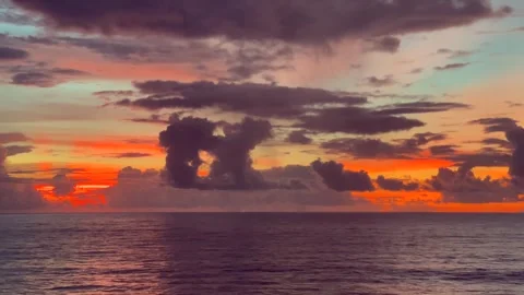 Clouds are illuminated by a vibrant sunset over the ocean 動画素材 338282793