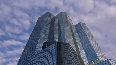 Clouds are reflected in a mirrored glass skyscraper in a business district Stock Footage 220854552