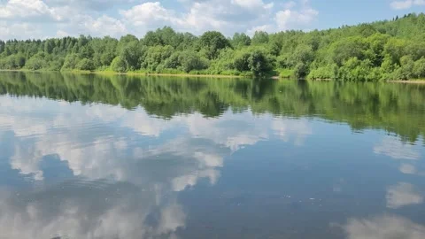 Clouds are reflected in the river. Forest on the river bank. Beautiful landscape Video stock 245496508