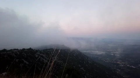 Clouds assault on top of a mountain 動画素材 137961360