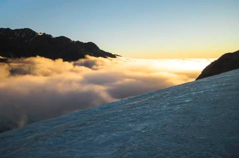 Clouds blanket the Fox Glacier during sunset in New Zealand Stock Photos