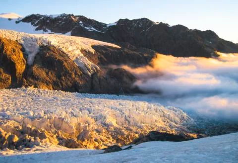Clouds blanket the Fox Glacier during sunset in New Zealand Stock Photos