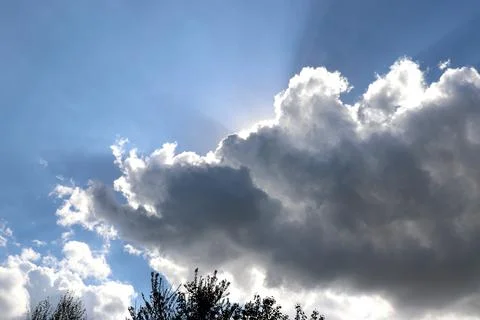 Clouds blocking sun- sunlight from behind clouds over tree tops Stock Photos