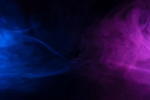 Clouds of blue and purple colored smoke swirling on black table background Stock Photos