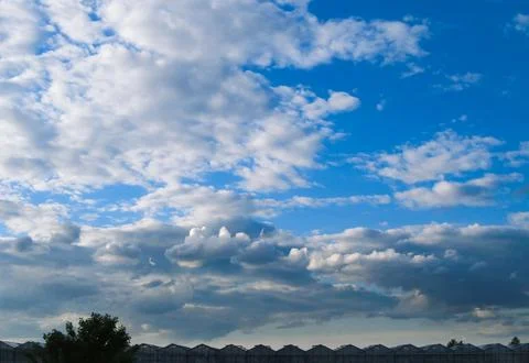 Clouds in the blue sky above the triangular roofs of greenhouses Stock-Fotos