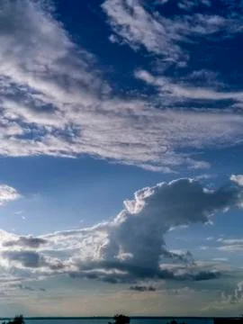 Clouds on the blue sky against the background of the stripes of the lake Stock Illustration