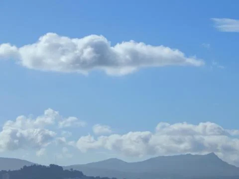 Clouds in the blue sky over mountains Stock Photos