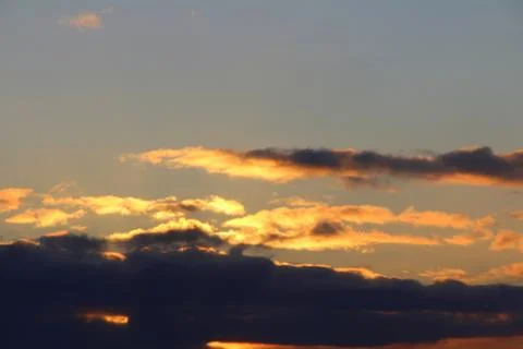 Clouds in the blue sky at sunset or dawn backlit by the sun. Place for text a Stock Photos