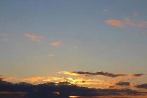 Clouds in the blue sky at sunset or dawn backlit by the sun. Place for text a Stock Photos