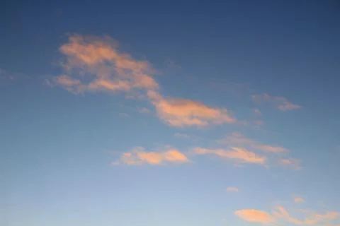 Clouds in the blue sky at sunset or dawn backlit by the sun. Place for text a Stock Photos