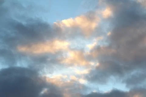 Clouds in the blue sky at sunset or dawn backlit by the sun. Place for text and Stock Photos