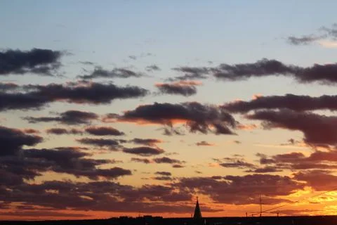Clouds in the blue sky at sunset or dawn backlit by the sun. Place for text and Stock Photos