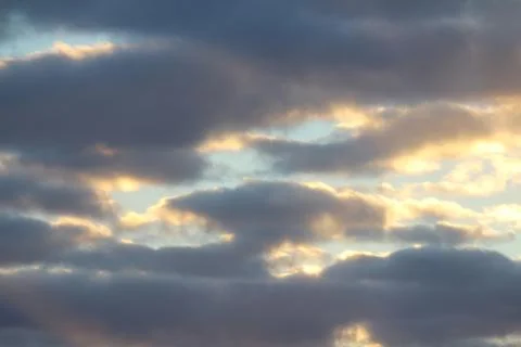 Clouds in the blue sky at sunset or dawn backlit by the sun. Place for text and Stock Photos