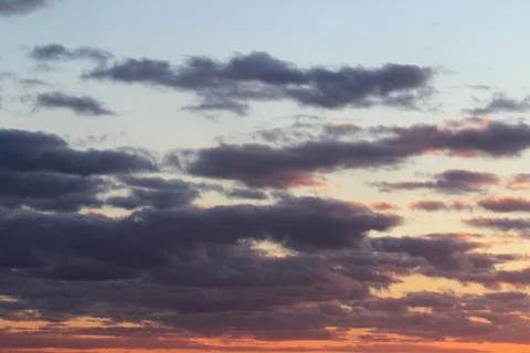 Clouds in the blue sky at sunset or dawn backlit by the sun. Place for text and Stock Photos