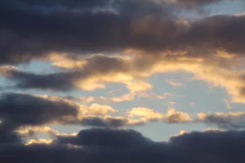 Clouds in the blue sky at sunset or dawn backlit by the sun. Place for text and Stock Photos