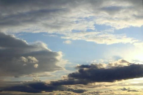 Clouds in the blue sky at sunset or dawn backlit by the sun. Place for text and Stock Photos