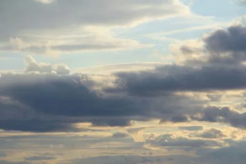 Clouds in the blue sky at sunset or dawn backlit by the sun. Place for text and Stock Photos