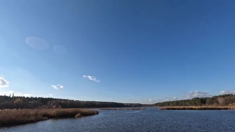 Clouds in the blue sky sweep over the lake in the forest. Stock Footage 196138747