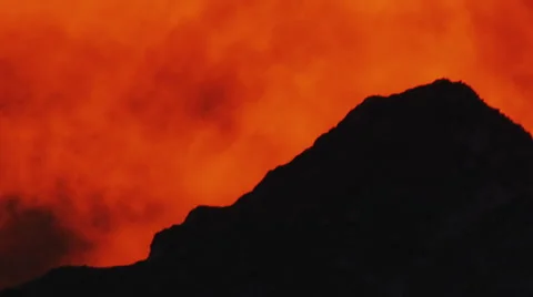 Clouds boil around mountain peak in fiery orange light of sunrise Stock Footage 62745576