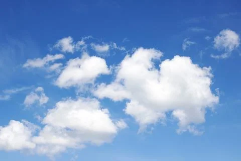 Clouds in a bright blue sky in sunlight Stock Photos