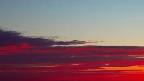 Clouds, brightly colored from below by the rays of the setting sun, float across Stock Footage 220622271