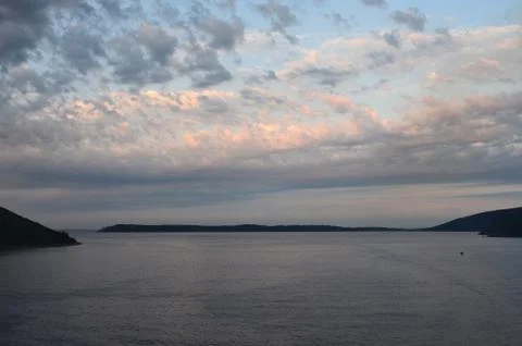 Clouds capturing the last light of sunset over a bay. Stock Photos