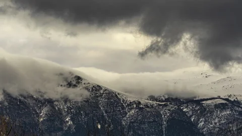 Clouds carried by the north wind climb over the white peaks. Timelapse. Stock Footage 150839254