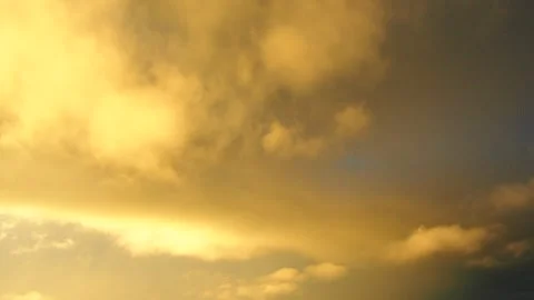 Clouds change color to gold as the sun sets over the horizon. The sky lights up  Stock Footage 343738905