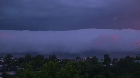 Clouds cover the sky above a residential area as the sun sets, creating a Stock Footage 344440944