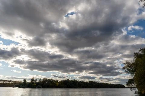Clouds cover the sky over a river during late afternoon in a natural setting Stock Photos
