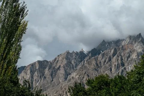 Clouds covered snow capped mountain peaks in karakoram range. Stock Photos