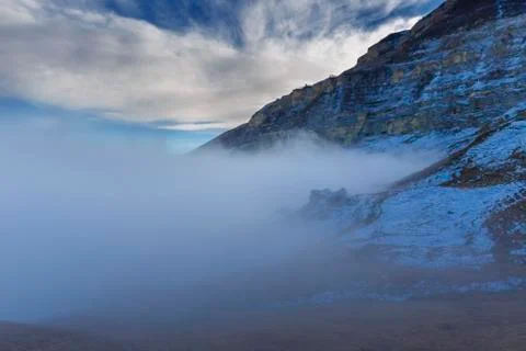 Clouds creeping below mountains Stock Photos