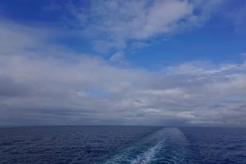 Clouds in a deep blue sky and the wake of a cruise ship in the Gulf of Alaska Foto stock