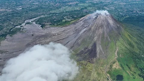 Clouds drift at eye level with Sinabung crater, where thin plumes of steam rise Stock Footage 328630199