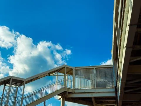 Clouds drift over a staircase leading to a platform in a busy city during m.. 写真素材