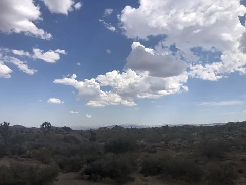 Clouds Drift Peacefully Over a Serene Desert Landscape Under a Bright Sky Stock Photos