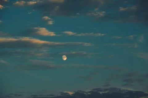 Clouds drift in sky as moon shines bright during evening hours in  tranquil s Stock Photos