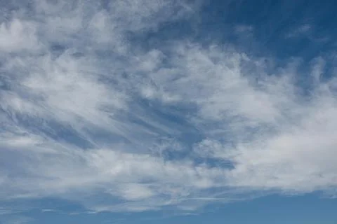 Clouds drift slowly across a bright blue sky in midday Stockfoto's