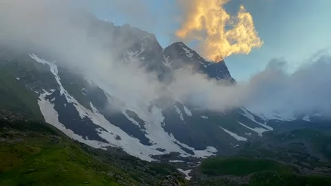 Clouds drifting across Chaukhi Massif cover snow-lined peaks 库存影片 340387254