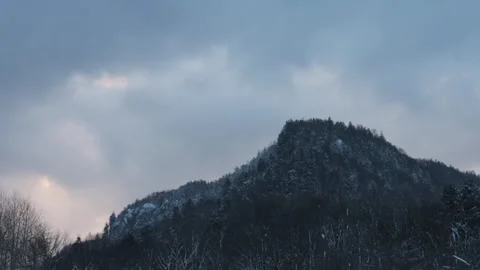 Clouds drifting behind a dark mountain peak at dawn Stock Footage 303256505