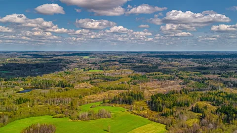 Clouds drifting over farmland and forested landscapes - drone time lapse Stock Footage 309199045