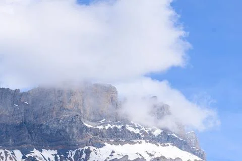 Clouds drifting over rocky alpine cliff Stock Photos