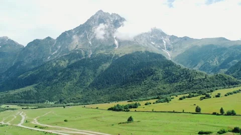 Clouds embracing majestic mountain peak over lush green valley 库存影片 301233059