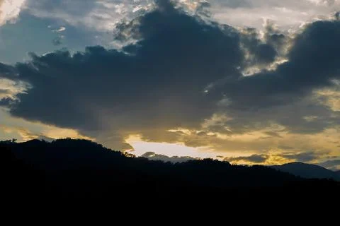 Clouds fill sky above  mountain range during sunset. colors change as dayligh Stock Photos