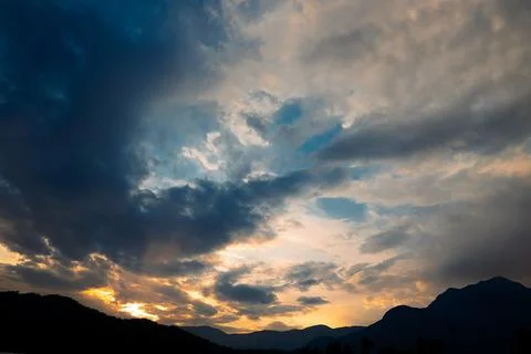 Clouds fill sky above  mountain range during sunset. colors change as dayligh Stock Photos