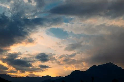 Clouds fill sky above  mountain range during sunset. colors change as dayligh Stock Photos